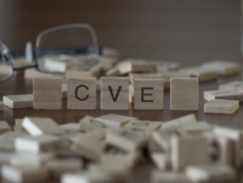 Scrabble tiles scattered in front of some glasses with a few standing up that spell out CVE